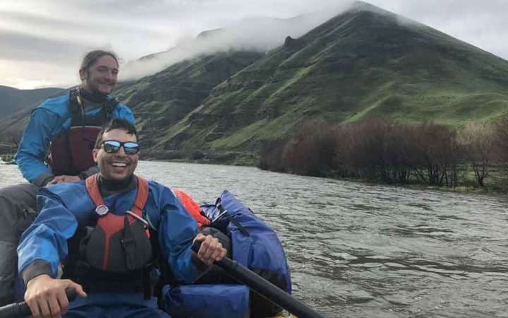 two gap year students smile while navigating a raft on an outward bound course 